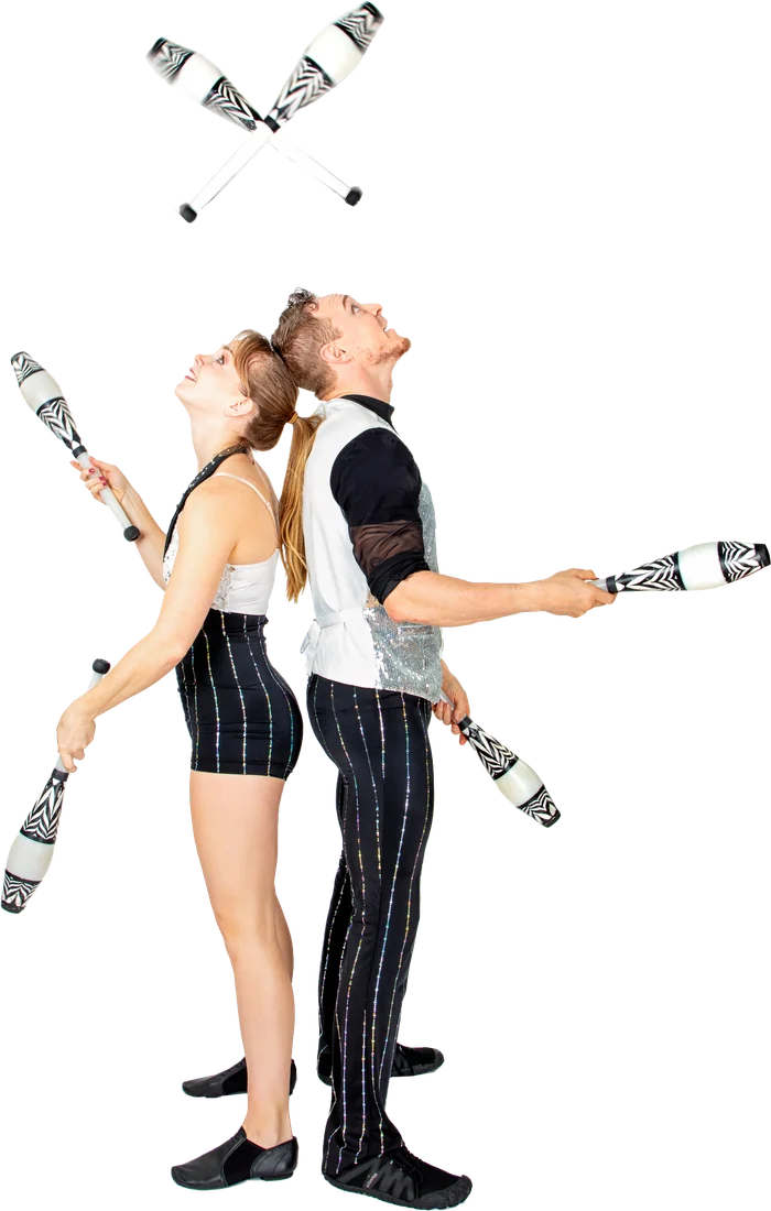 Rocco and Nova standing back to back, juggling clubs