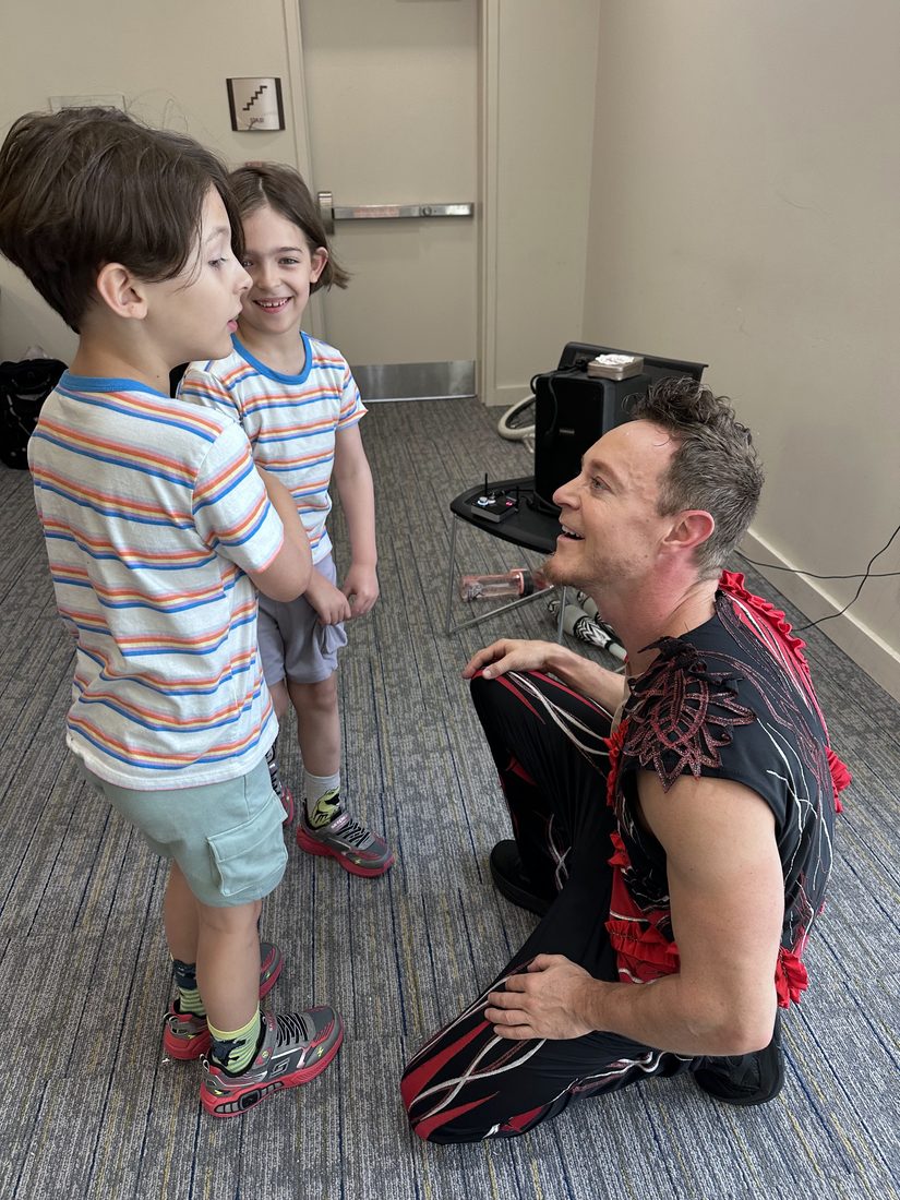 Rocco kneeling to chat with two young boys
