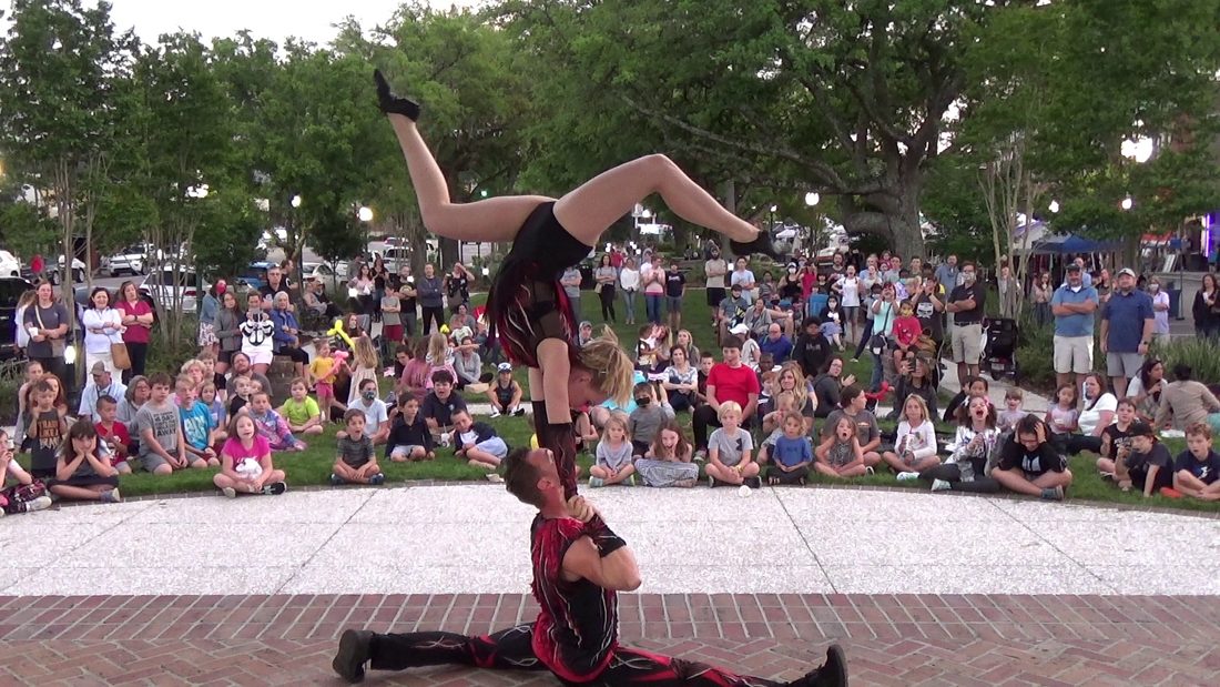 Rocco and Nova performing acrobatics outdoors in front of a huge crowd of kids sitting on the grass